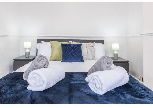 a bedroom with a large bed with white towels and pillows at Modern 3BD House in Salford, with free parking in Manchester