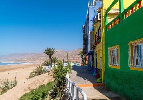 a green and yellow building next to a beach at Dar Mogador Sun near Taghazout - Surf, Sea, colorful village in Taghazout