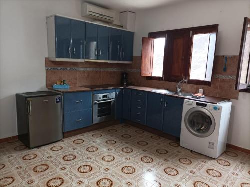a kitchen with blue cabinets and a washing machine at Vivienda Vacacional Casa Uca in San Pedro