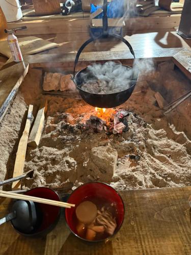 a pan over a fire with some food on it at guesthouse 古民家の宿屋千鶴 1階2号室部屋貸し in Hiroshima