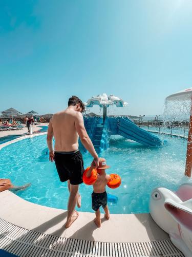 a man and a boy in the water at a pool at Elounda Residence Resort & Waterpark in Elounda