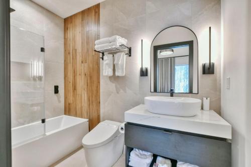 a bathroom with a sink and a toilet and a mirror at Tremblant mountain view PH71 in Mont-Tremblant