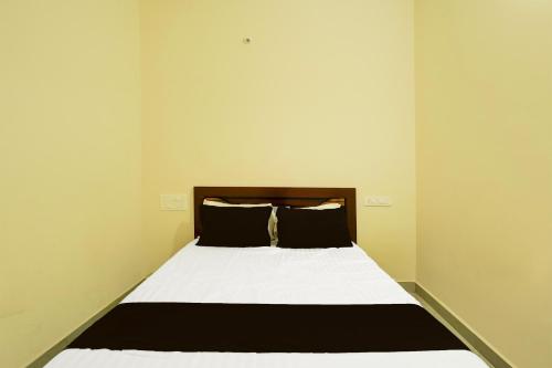 a bedroom with a bed with white sheets and black pillows at SPOT ON Mango Leaf Restaurant in Bayappanhalli