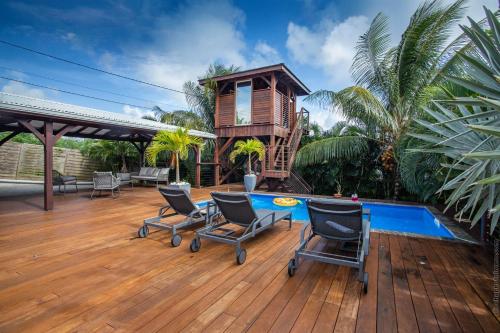 a house with a deck with chairs and a pool at Villa Sweet Paradise in Le Lamentin