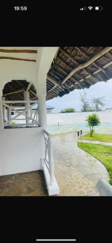 a white bench sitting under a building near the water at Poa Poa Villas in Watamu