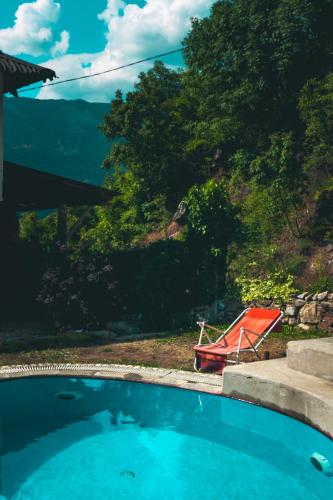 a red chair sitting next to a swimming pool at Villa Gorno Melnicani in Debar