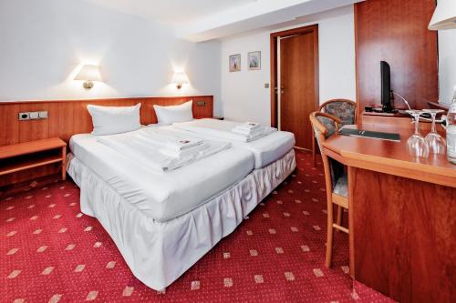 a hotel room with a large bed and a desk at Hotel Domschatz in Quedlinburg