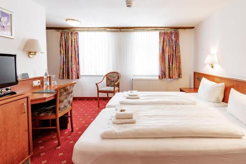 a hotel room with two beds and a desk at Hotel Domschatz in Quedlinburg