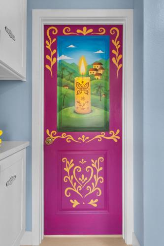 a purple door with a painting of a candle at Enchanted Dreams: Theater, Arcades, Playground + in Neff