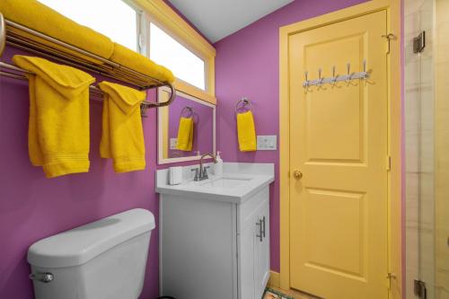 a bathroom with a toilet and a sink and a yellow door at Enchanted Dreams: Theater, Arcades, Playground + in Neff