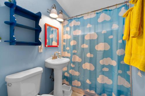 a bathroom with a blue shower curtain with clouds at Enchanted Dreams: Theater, Arcades, Playground + in Neff