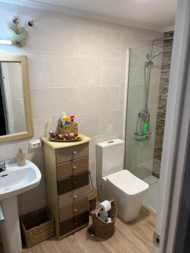 Un baño con inodoro, lavabo y ducha. en Apartamento en la playa, en La Mata