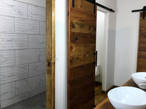 a bathroom with a wooden door next to a toilet at Quiet Retreat, Ideal For An Intimate Romantic Getaway Or 2 Couples in Roatan