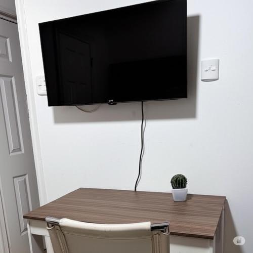 a television hanging on a wall with a wooden table at Brisa rent a home in Tocopilla