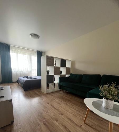a living room with a green couch and a bed at 2-jų kambarių nuoma in Mažeikiai