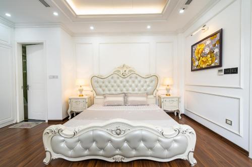 a white bed in a white room with two tables at Lumiere Villa Splendora An Khánh in Vân Lũng