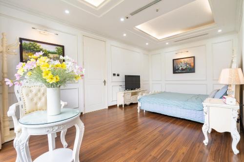 a bedroom with a bed and a table with a vase of flowers at Lumiere Villa Splendora An Khánh in Vân Lũng