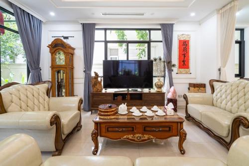a living room with two couches and a tv at Lumiere Villa Splendora An Khánh in Vân Lũng