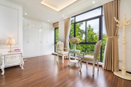 a living room with a table and chairs and a large window at Lumiere Villa Splendora An Khánh in Vân Lũng