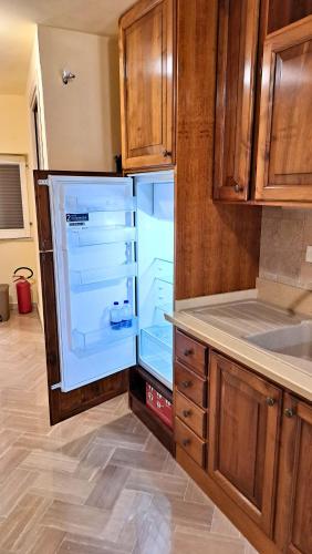 an empty refrigerator in a kitchen with wooden cabinets at Silvia House in Prossedi
