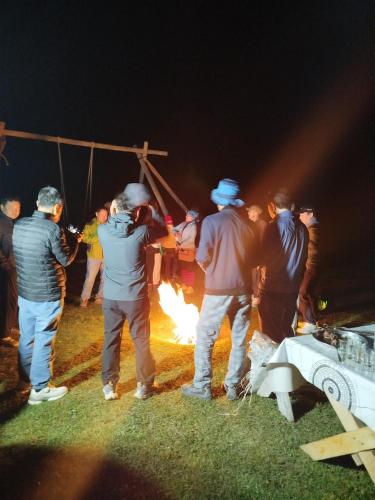 a group of people standing around a fire at night at Mira Guest House in Kyzart