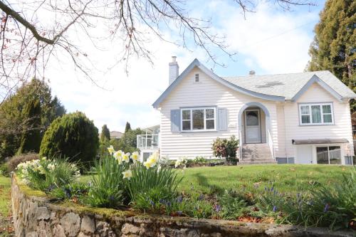 a white house with flowers in the yard at Victoria Gorge Waterway Vacation Home in Victoria