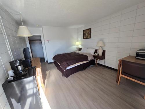 a hotel room with a bed and a television at Camelot Court Motel in Prince George