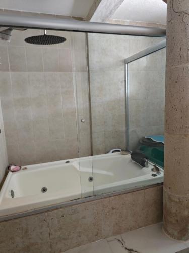 a bath tub with a glass wall in a bathroom at Céntrico León Guanajuato México in Sofía