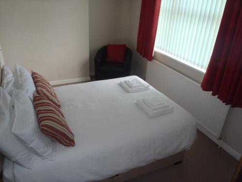 a white bed with two pillows and a chair in a bedroom at Clinmore House in Paignton