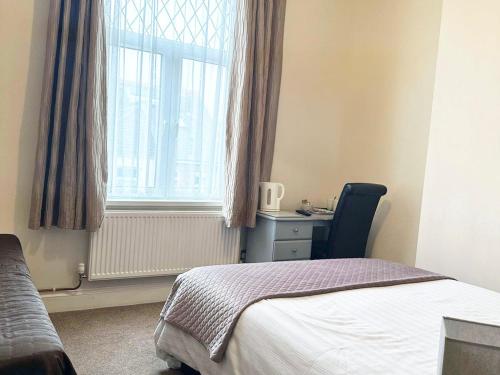 a bedroom with a bed and a window and a desk at Esk Vale Guest House in Portsmouth