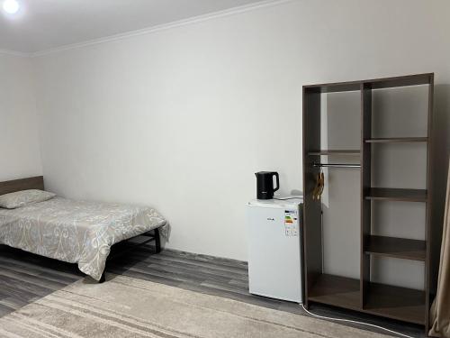 a small room with a bed and a refrigerator at Guest house Stella in Cholpon-Ata
