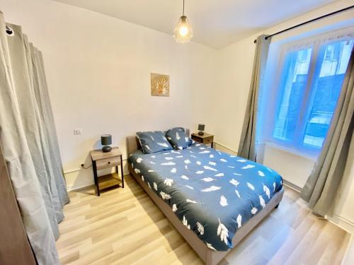 a bedroom with a bed with blue sheets and a window at Charmant 3 pièces in Saint-Claude