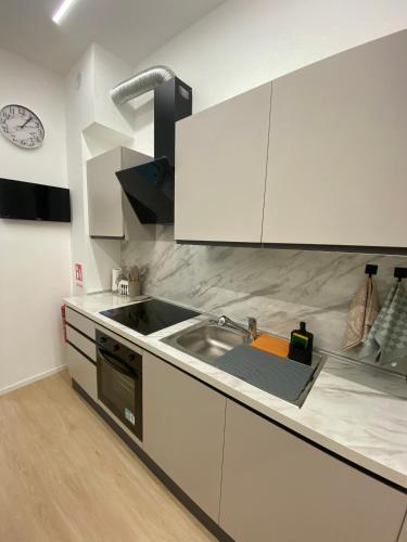 a kitchen with white cabinets and a sink and a clock at Mare Montenotte in Savona
