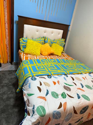 a bed with colorful sheets and pillows on it at B&B apartments in Yaoundé