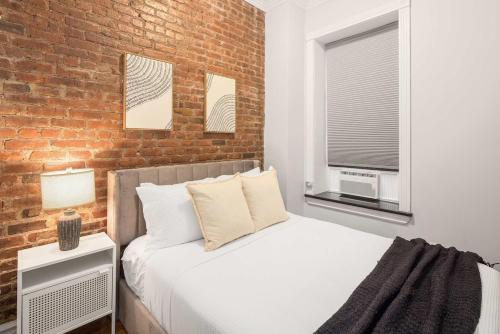 a bedroom with a bed and a brick wall at Trendy Nolita Stay Walk to SoHo & Little Italy in New York