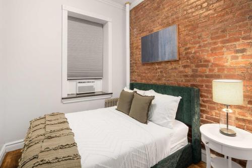 a bedroom with a bed and a brick wall at Trendy Nolita Stay Walk to SoHo & Little Italy in New York