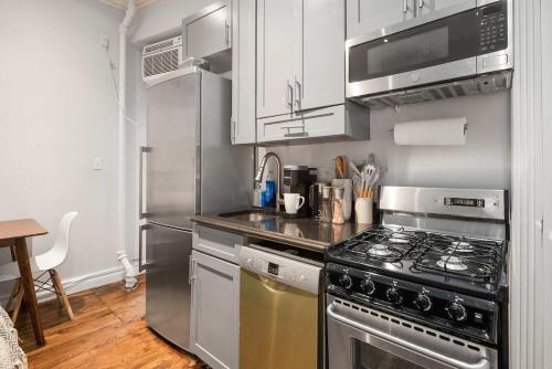 a kitchen with a stove and a microwave at Trendy Nolita Stay Walk to SoHo & Little Italy in New York