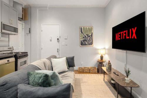 a living room with a couch and a tv on a wall at Trendy Nolita Stay Walk to SoHo & Little Italy in New York