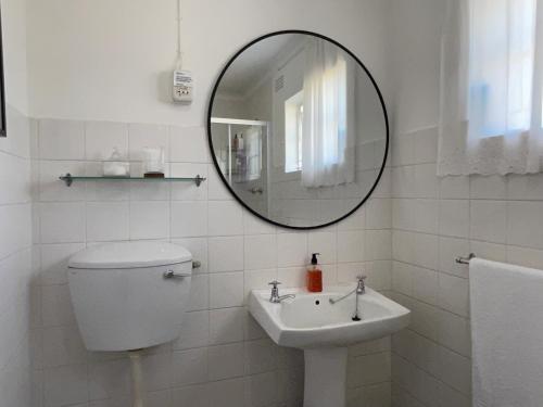 a white bathroom with a sink and a mirror at Albert Manor guest house in Ladismith