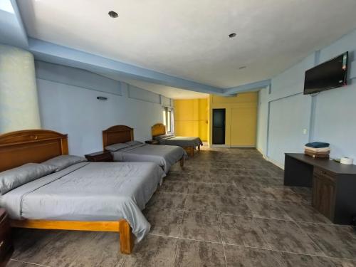 a room with four beds and a flat screen tv at hotel hao han in Ciudad Hidalgo