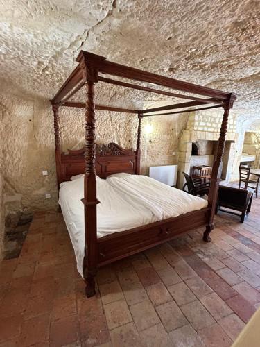 a bedroom with a canopy bed in a stone room at Habitat troglodyte typique et confortable in Villaines-les-Rochers