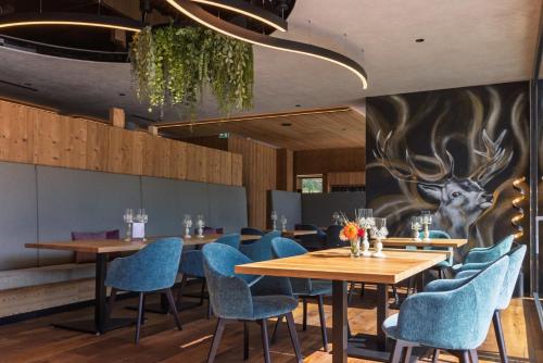 a restaurant with wooden tables and blue chairs at Hotel Acherl in Achenkirch