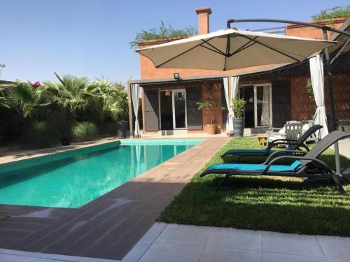 a pool with two chairs and an umbrella at Villa Roseaux heated pool Marrakech in Najem