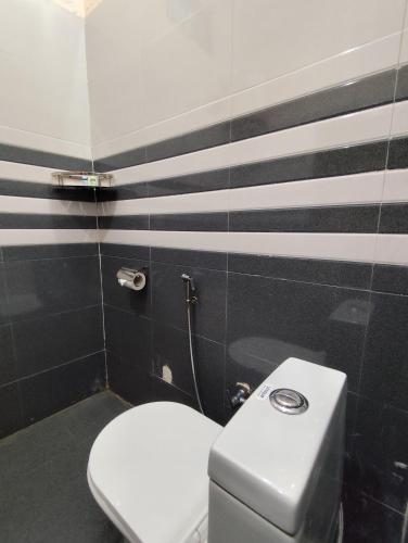a toilet in a bathroom with black and white stripes at Geetanjali Palace Hotel & Restaurant in Rudraprayāg