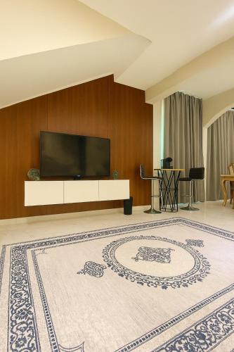 a living room with a television and a large rug at Jasmine Corner Chalet in Mawāliḩ