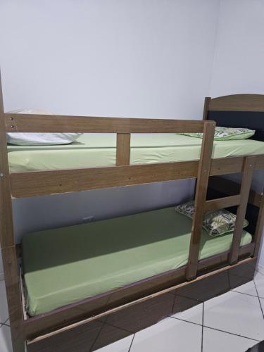 a wooden bunk bed with green sheets on it at Apto em Itapecerica da Serra in Itapecerica da Serra