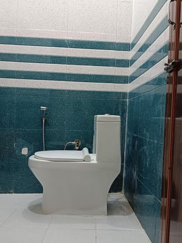 a white toilet in a bathroom with a green wall at Geetanjali Palace Hotel & Restaurant in Rudraprayāg