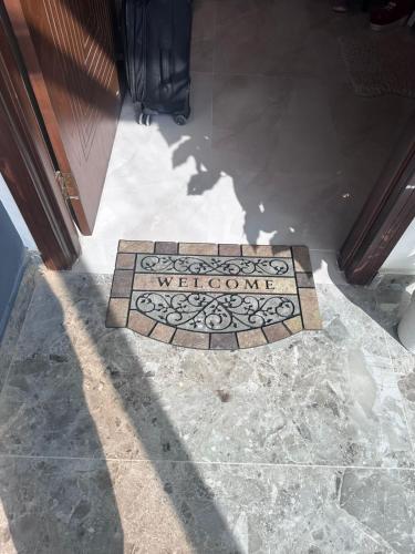 a welcome sign on a tile floor in front of a door at Anayah Fam Rental in Rawalpindi