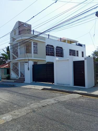 a white house with black gates on a street at Apartamentos ipap luperon in Puerto de Luperon