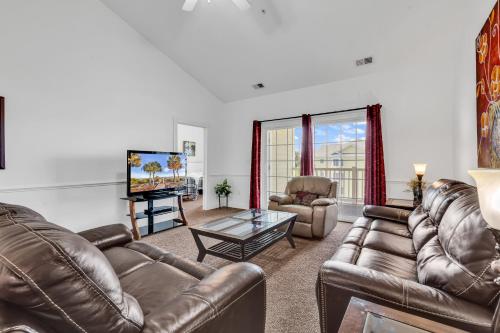 a living room with leather furniture and a flat screen tv at Myrtlewood by Monarch Rentals in Myrtle Beach